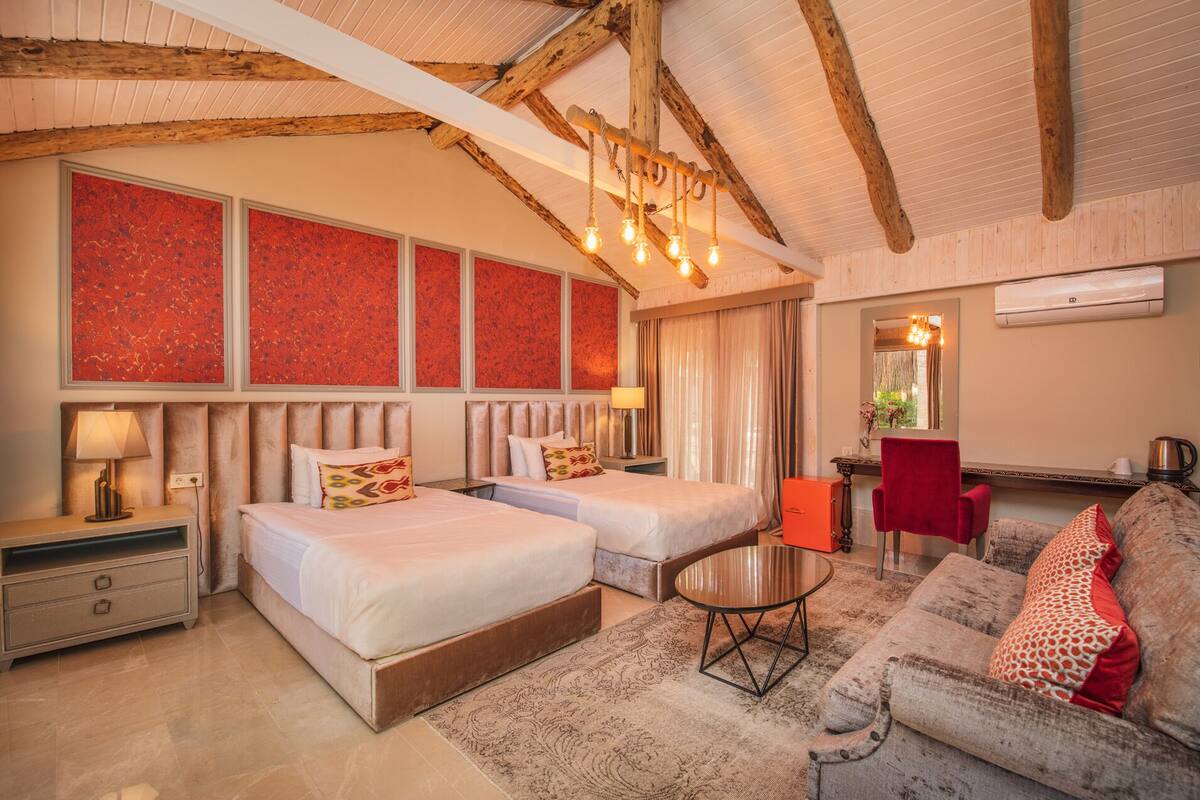 A hotel room with two beds, a sofa, a small table, and a mirror.