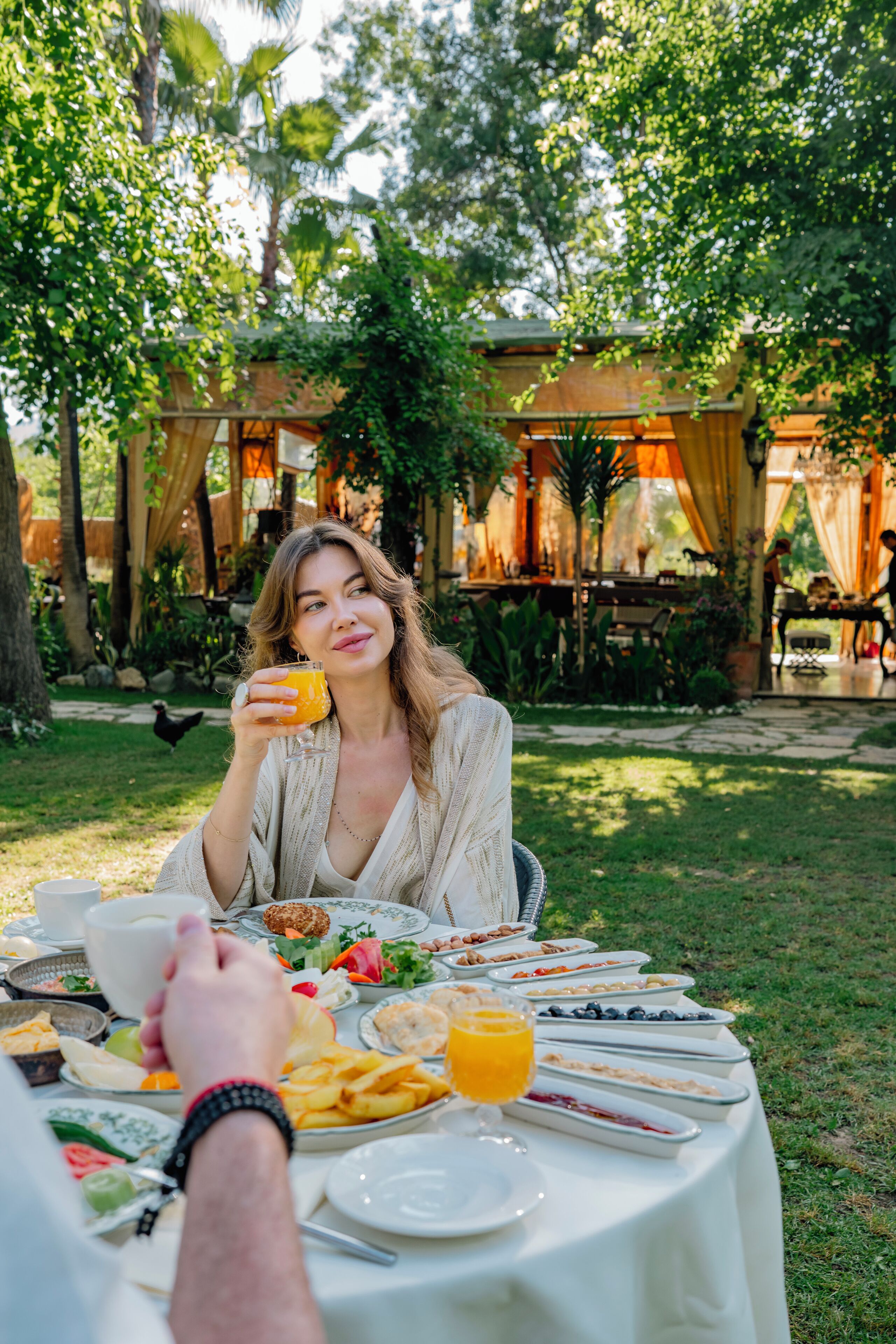 A dining table set outdoors with various dishes and a glass of orange juice.