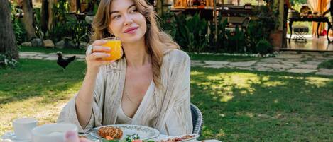 A dining table set outdoors with various dishes and a glass of orange juice.