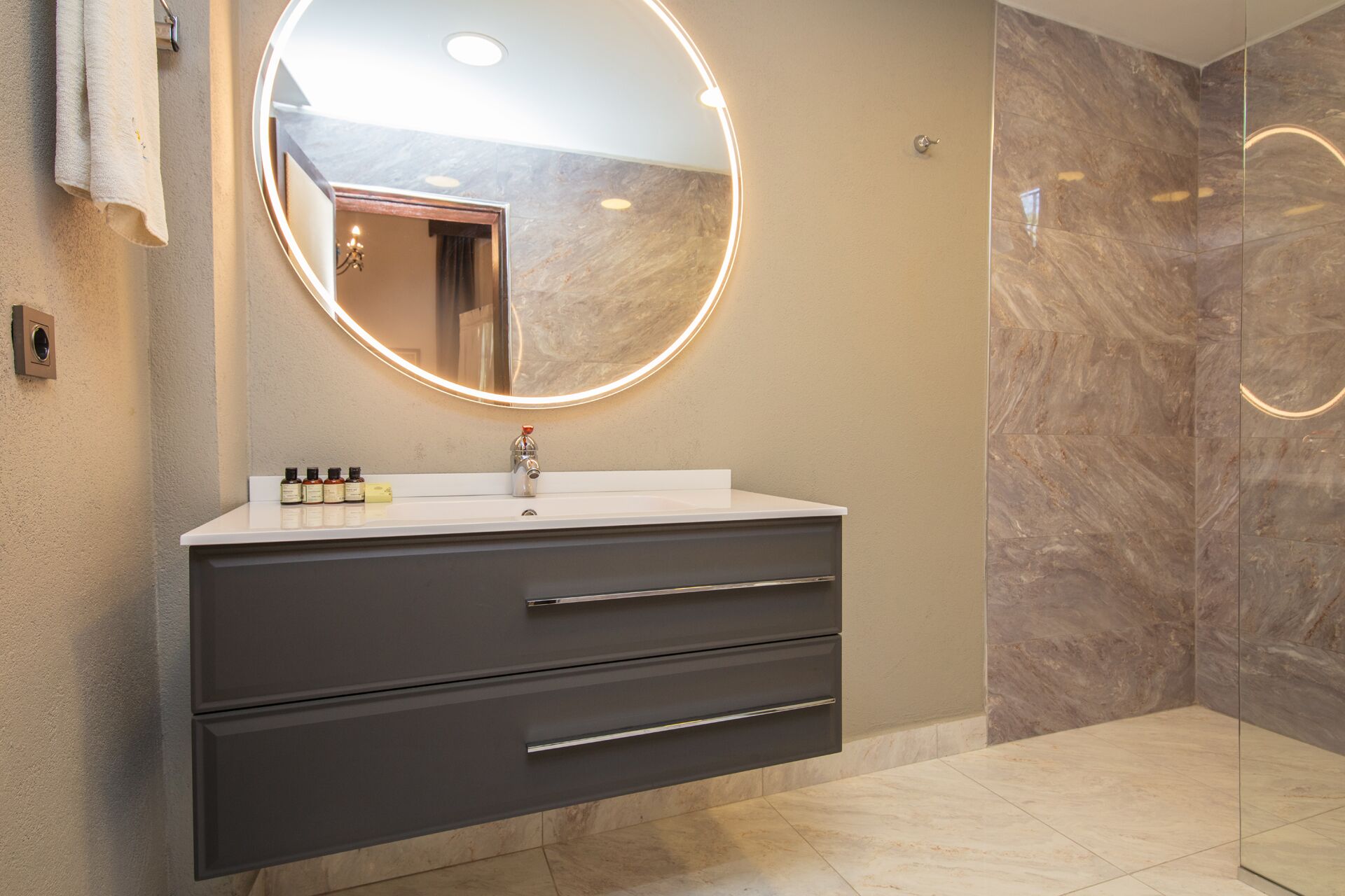 A modern bathroom with a round mirror, a sink, and a dark cabinet.
