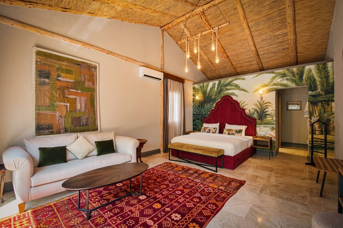 A room with a bed, a sofa, a coffee table, and a patterned rug.