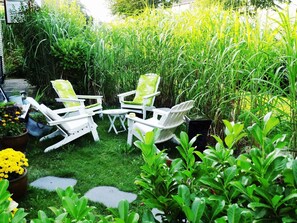 A garden with white chairs and a table, surrounded by lush greenery and plants. - Strandnest Büsum (Büsum)