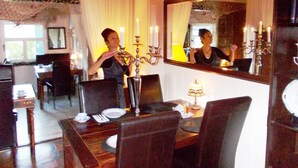 A dining area with a table set for two, a candelabra, and a mirror reflecting the room. - Strandnest Büsum (Büsum)