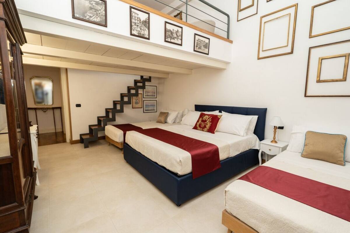 A bedroom with two beds, a staircase, and a balcony.