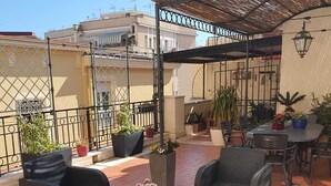 En tagterrasse med fletmøbler, plantekasser og et pergola.