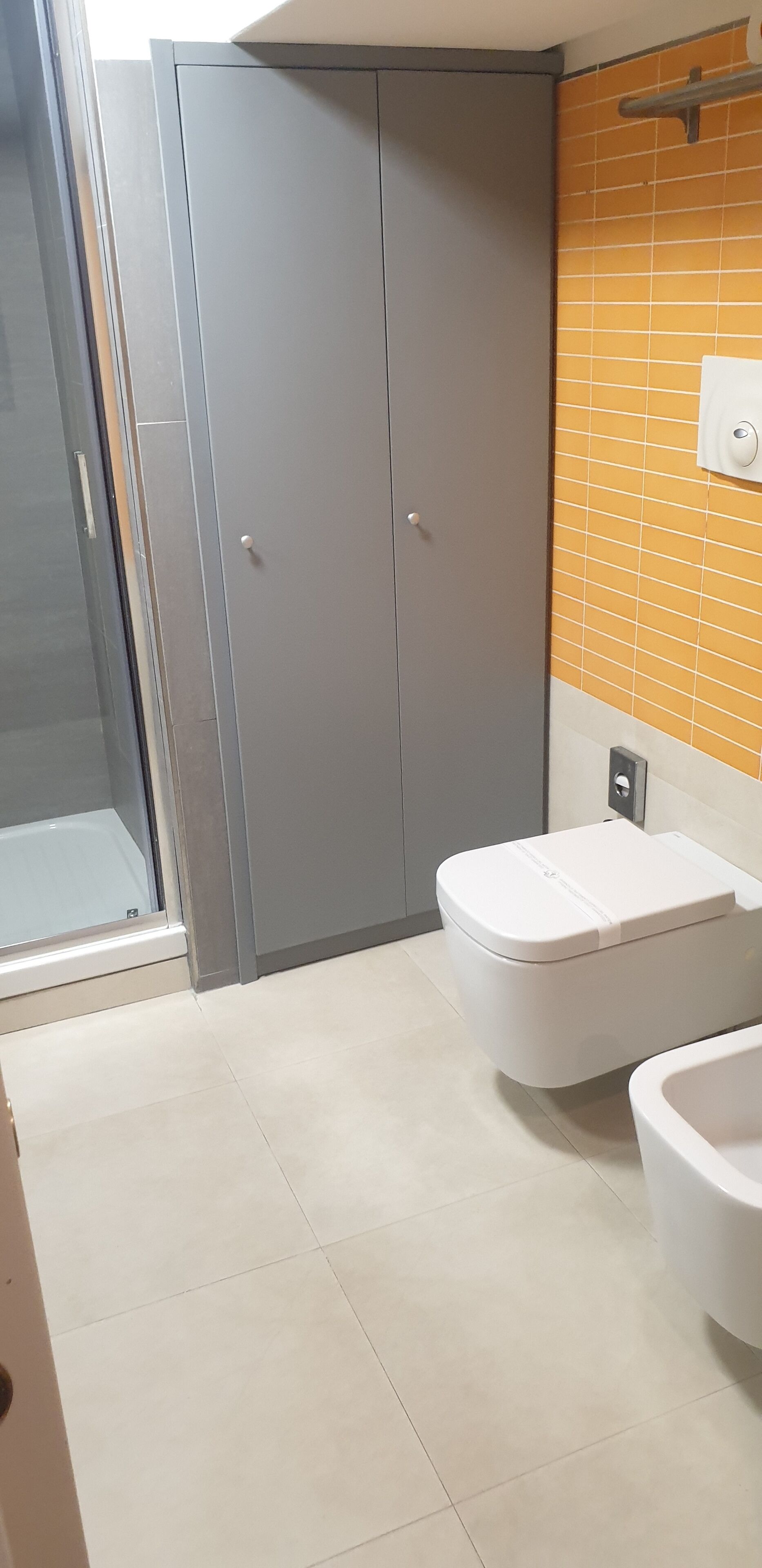 Et badeværelse med toilet, håndvask og bruseområde.