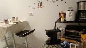 Una cocina con cafetera, tostadora y una pared decorada con motivos de café.