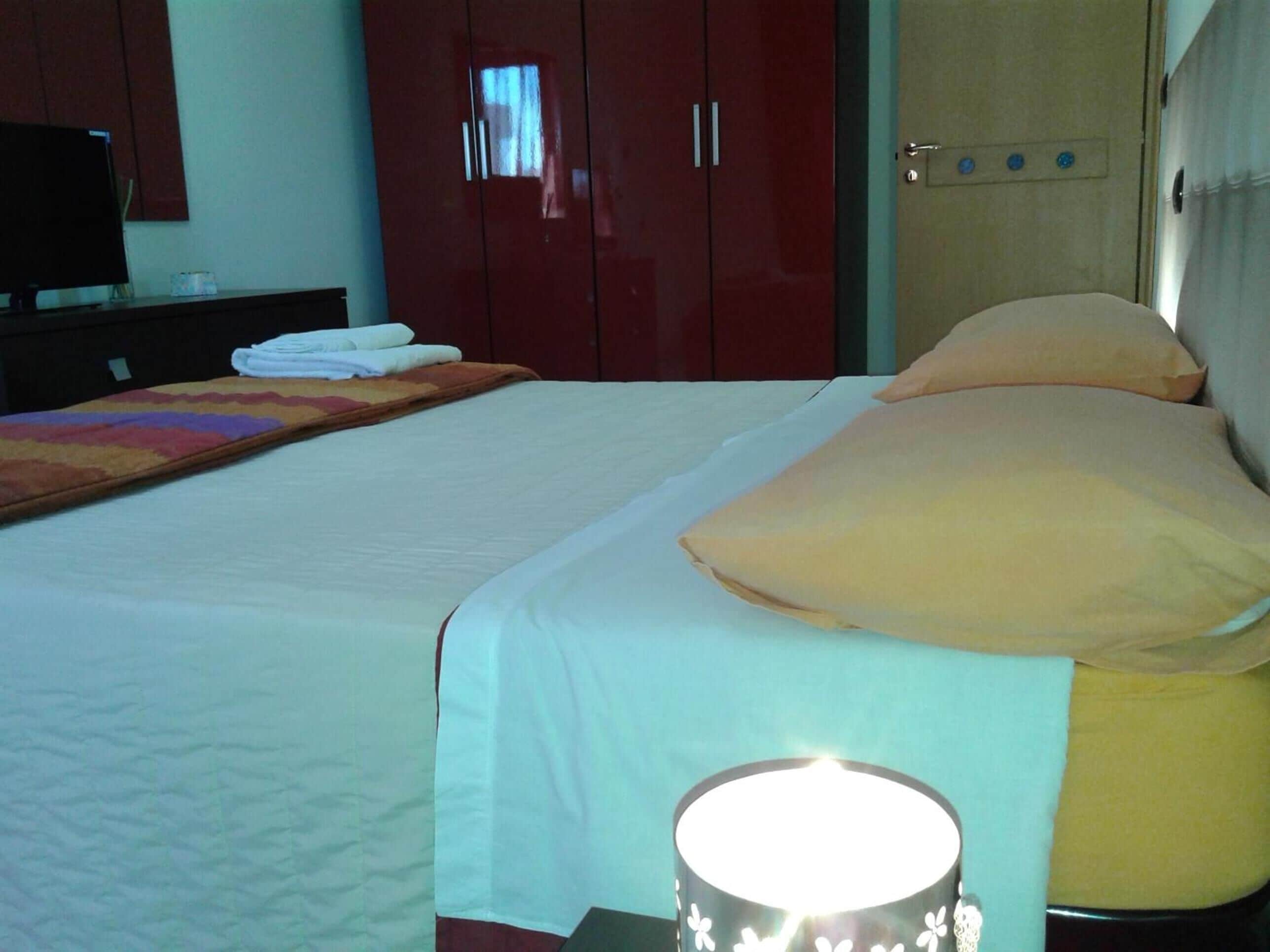 A hotel room with a bed, a television on a stand, and a wardrobe.