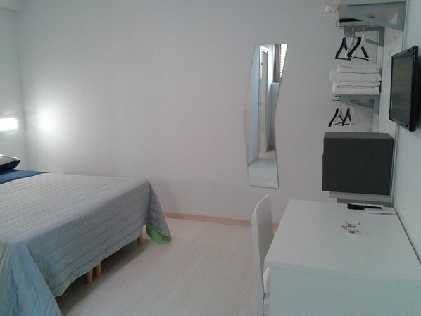 A bedroom with a bed, a desk, a chair, a TV, and a mirror. - I Gelsomini (Melfi)