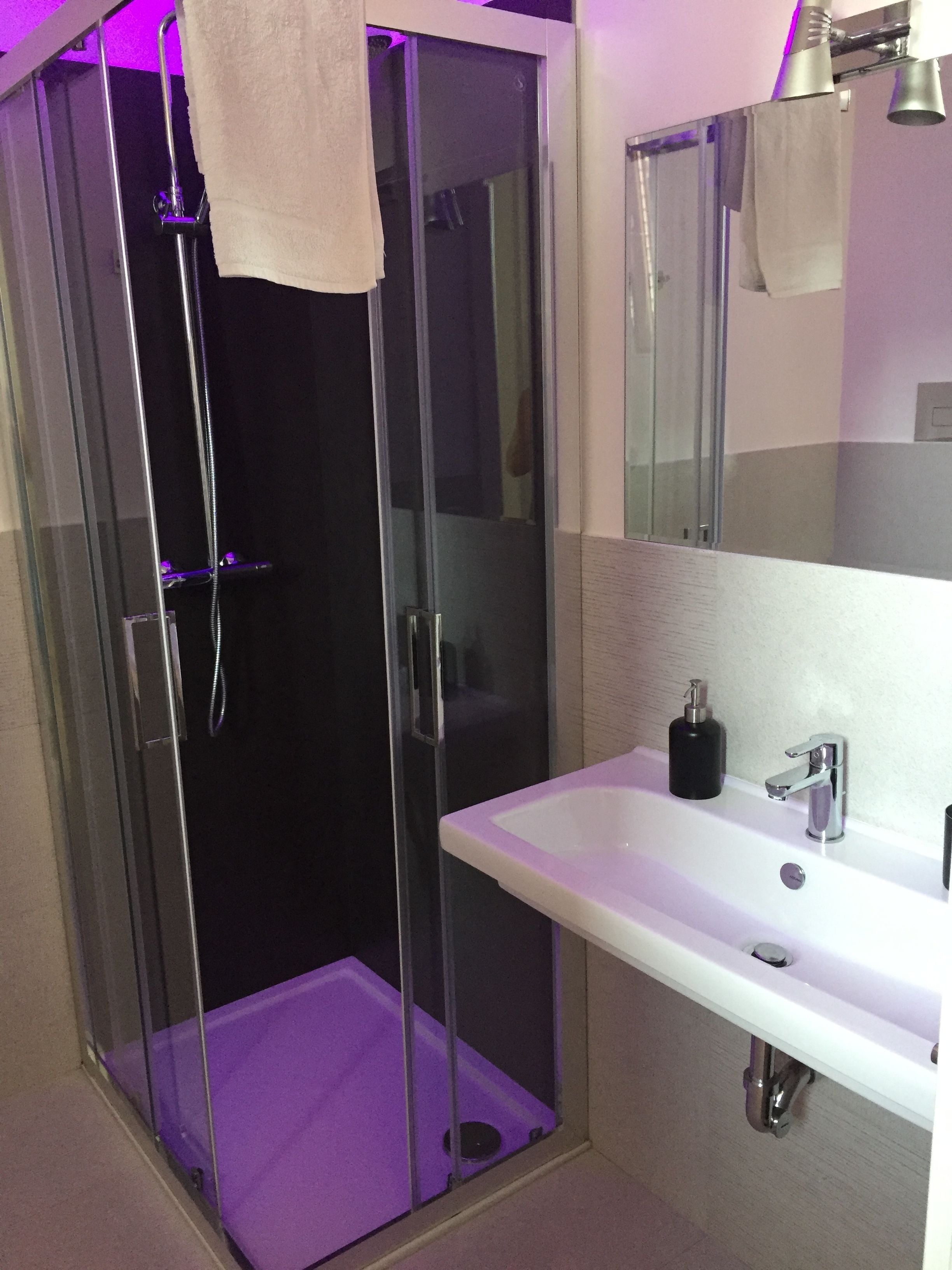 Une salle de bain moderne avec une douche à parois de verre, un lavabo blanc et un miroir au-dessus.