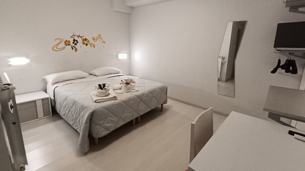 Una habitación de hotel moderna con una cama, mesitas de noche, un escritorio y un espejo.