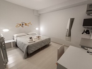 A modern hotel room with a bed, bedside tables, a desk, and a mirror. - I Gelsomini (Melfi)
