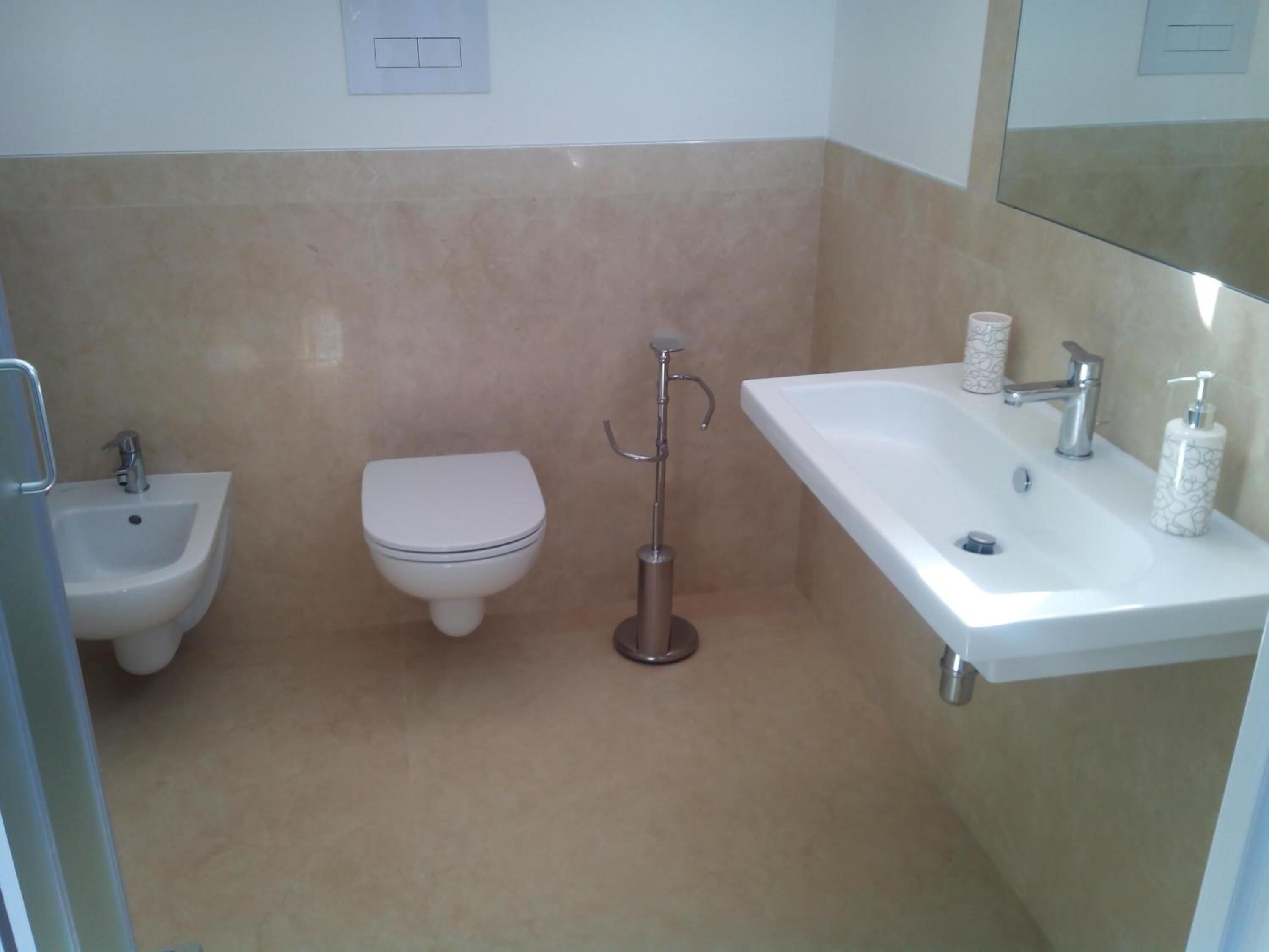 Une salle de bain équipée d’un bidet, de toilettes et d’un lavabo.