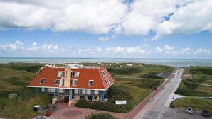 Un hotel con techo rojo, piscina y vista a la playa.