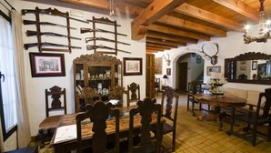 A dining area with wooden furniture, a chandelier, and mounted rifles on the wall. - Hotel Rural Molino la Boticaria (Marchena)