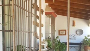 A courtyard with a wrought iron gate, potted plants, a bench, and a tiled floor. - Hotel Rural Molino la Boticaria (Marchena)