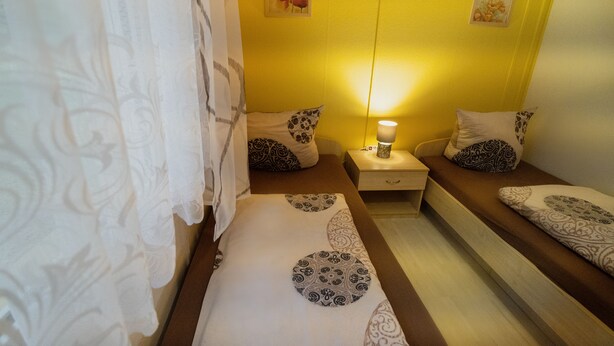 A room with two beds, each with patterned pillows and a bedside table with a lamp. - Bad Sonnenland (Moritzburg)