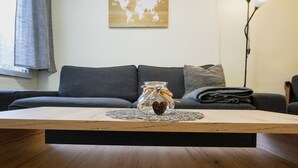 Una sala de estar moderna con una mesa de centro de madera, un frasco de vidrio con un adorno de corazón y un mapa mundial en la pared.