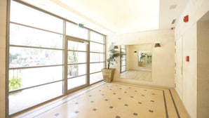 A hotel lobby with large windows, a potted plant, and a tiled floor. - Rental Israel - Mamilla Residences (Jerusalem)