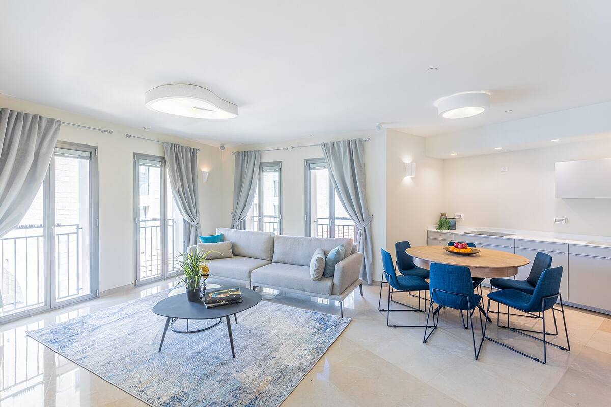 A modern living room with a sofa, a coffee table, and a dining area with chairs.