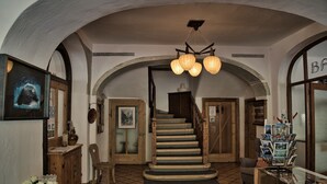 A staircase with wooden railings, a chandelier, and a patterned floor.