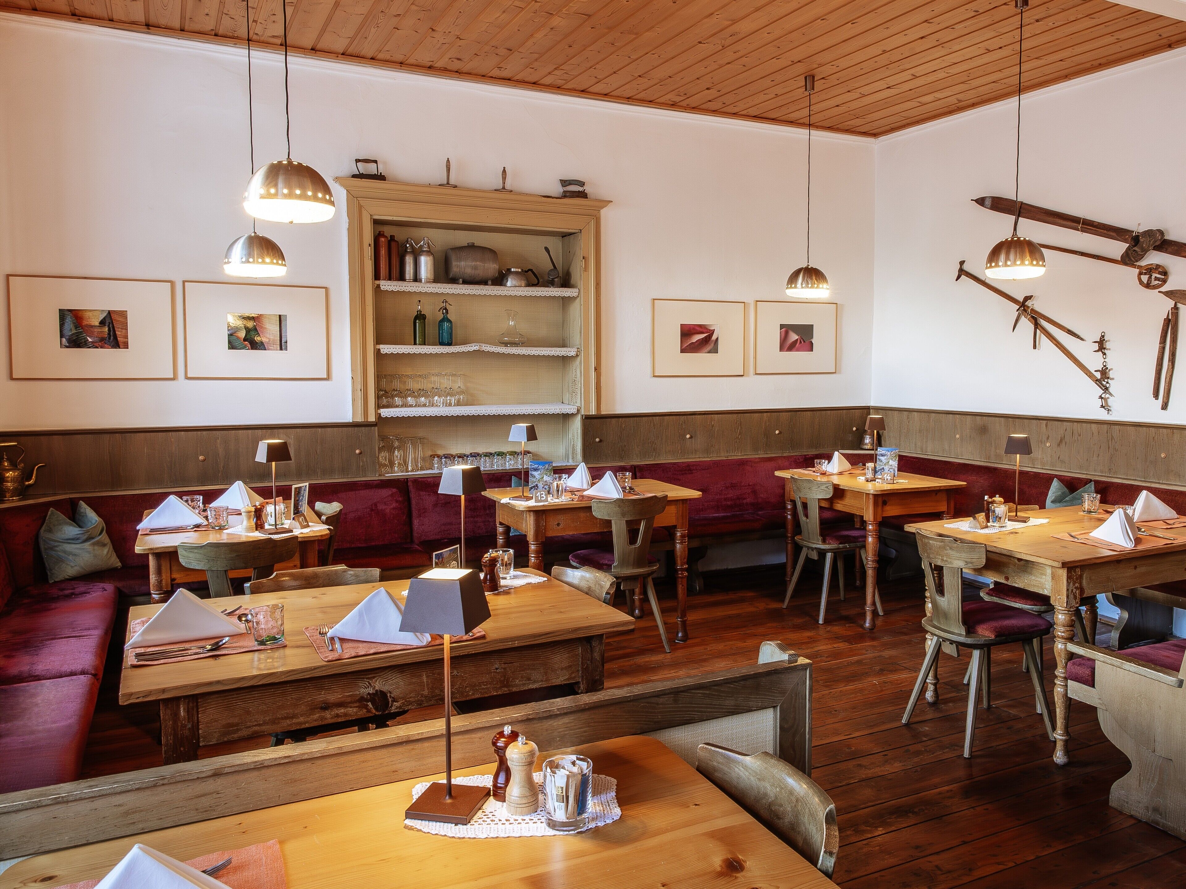 A restaurant interior with wooden tables, red upholstered booths, and hanging light fixtures.