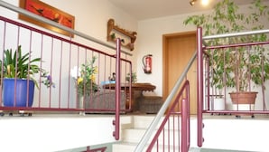 Un escalier avec des rampes rouges, des plantes en pot et un extincteur fixé au mur.