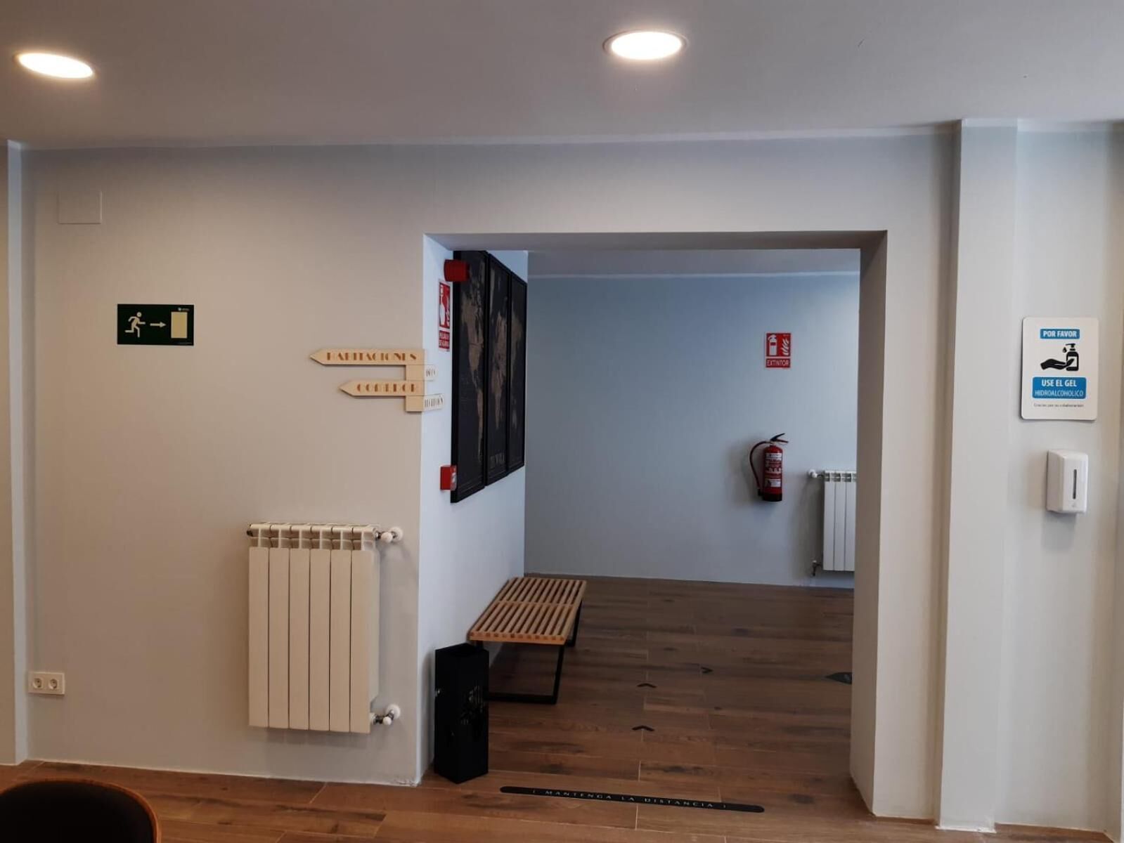 A hallway with directional signs, a fire extinguisher, and a bench.