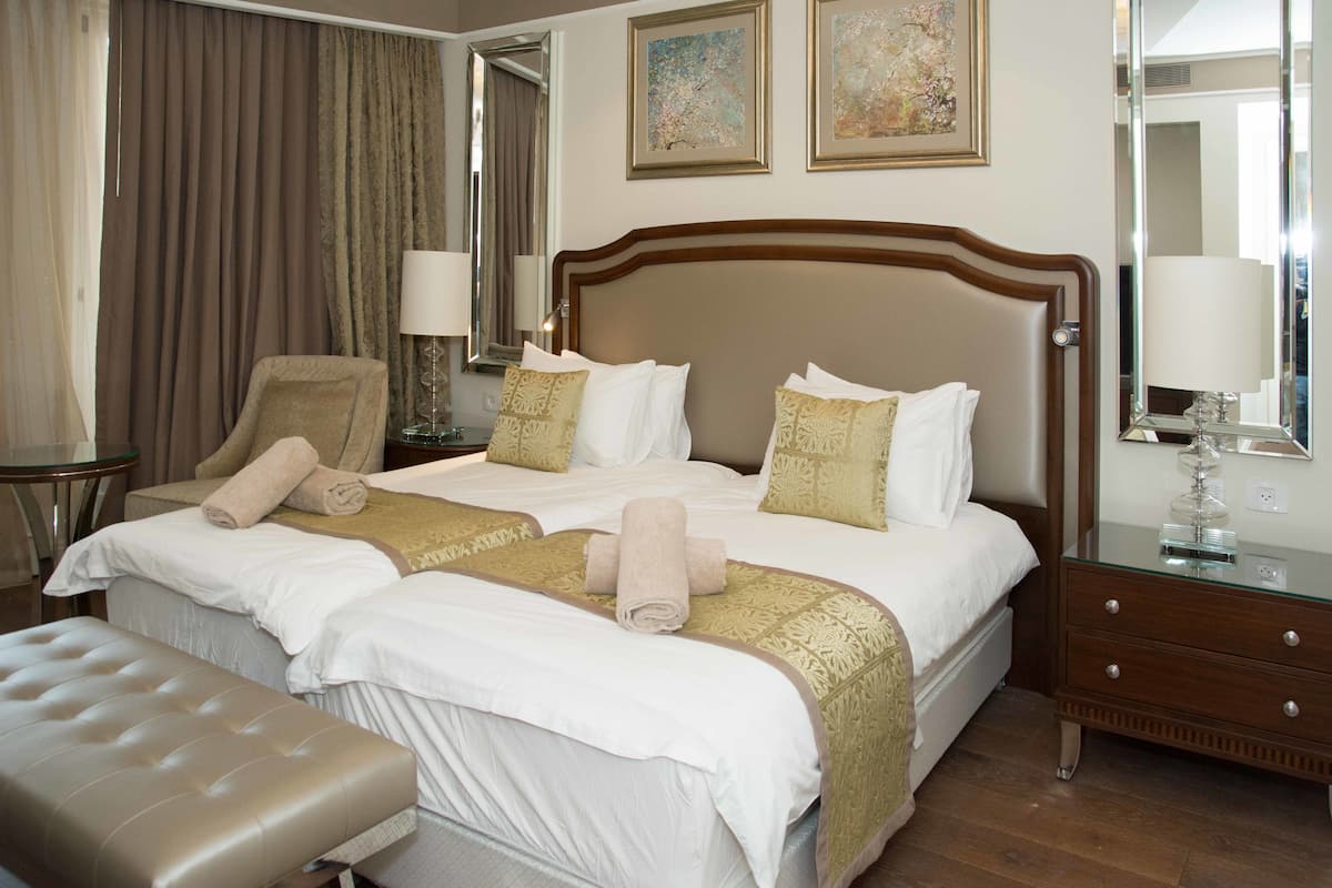 Une chambre d’hôtel avec un grand lit, un coin salon, un bureau et un miroir.