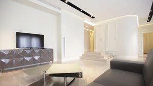 Een moderne woonkamer met een flatscreen televisie bevestigd aan een kast met geometrisch patroon, een minimalistische bank en een strakke salontafel.