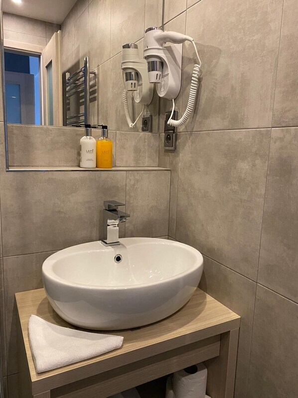A bathroom with a white sink, a towel, and a hairdryer mounted on the wall. - JBX Resort Apartments Lipno (Lipno nad Vltavou)