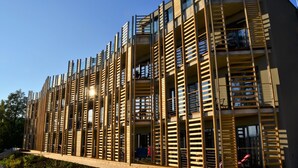 Een modern gebouw met meerdere balkons en een houten gevel.