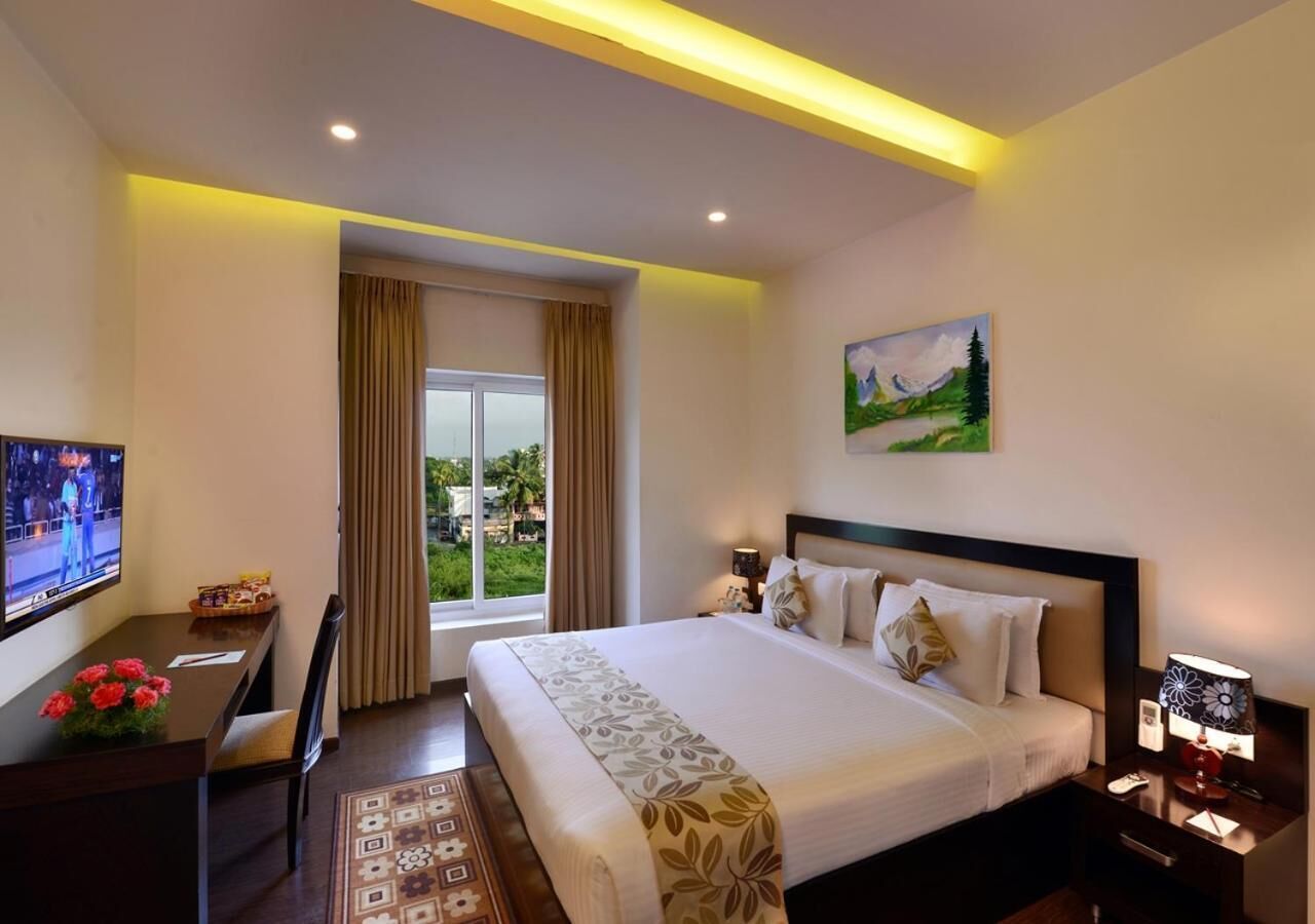 A hotel room with a bed, a desk, a TV, and a window with curtains.