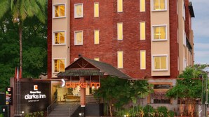 A multi-story hotel with a brick facade, large windows, and a covered entrance area with stairs.