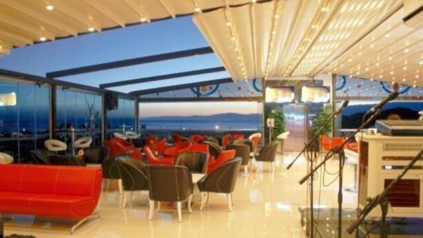 A modern outdoor seating area with a view of the sea, featuring red and black chairs and a red sofa. - Idahan Hotel (Burhaniye)