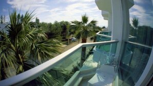 A modern balcony with glass railings overlooking a tropical garden with palm trees. - Idahan Hotel (Burhaniye)