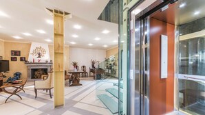 Un vestíbulo amplio con chimenea, zona de estar y entrada de cristal.