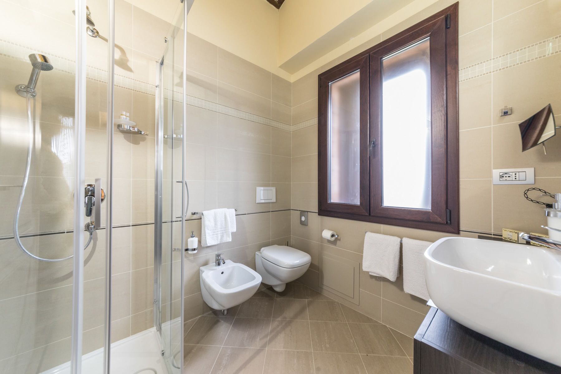 A modern bathroom with a glass-enclosed shower, a bidet, a toilet, and a large sink.