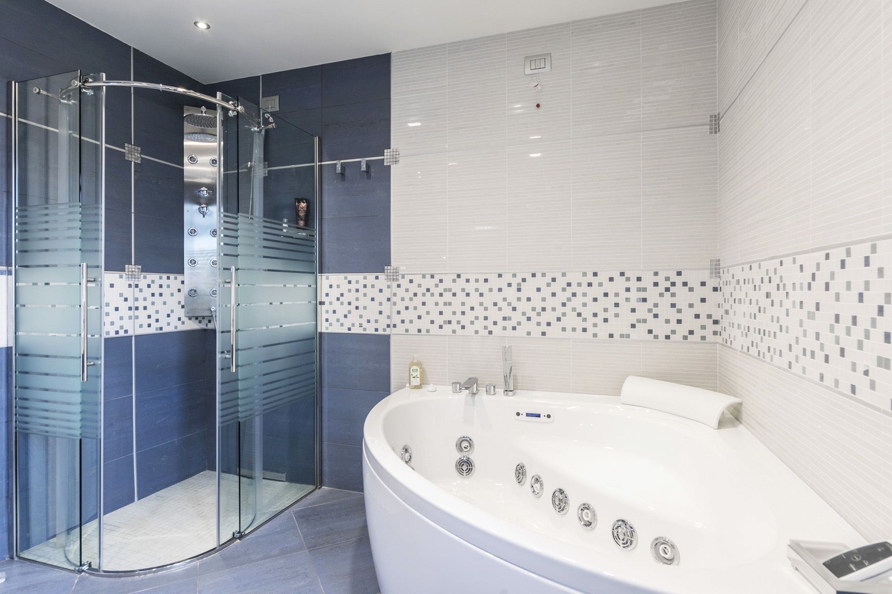 A modern bathroom with a glass-enclosed shower, a freestanding bathtub, and tiled walls.
