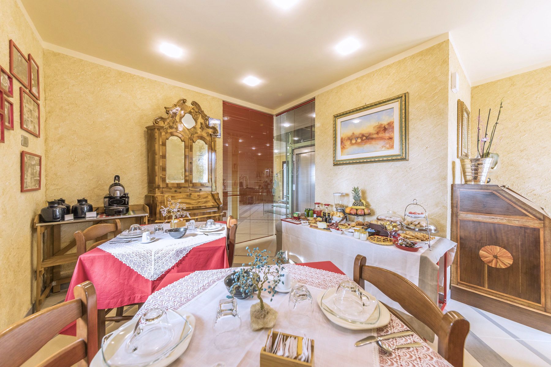 A dining area with tables set for a meal, a wooden cabinet, and a painting on the wall.