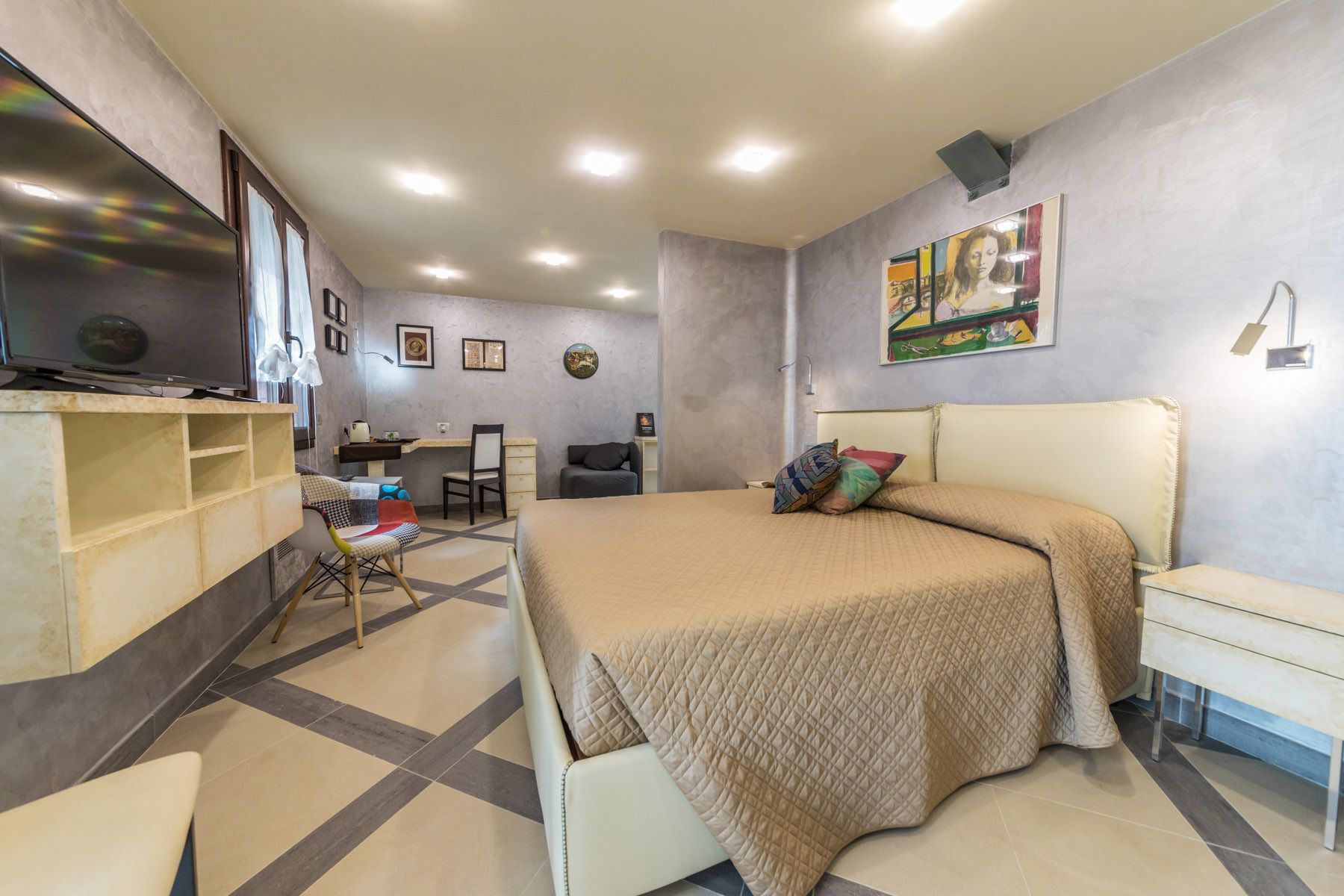 Een slaapkamer met een bed, bureau, stoel en een televisie.