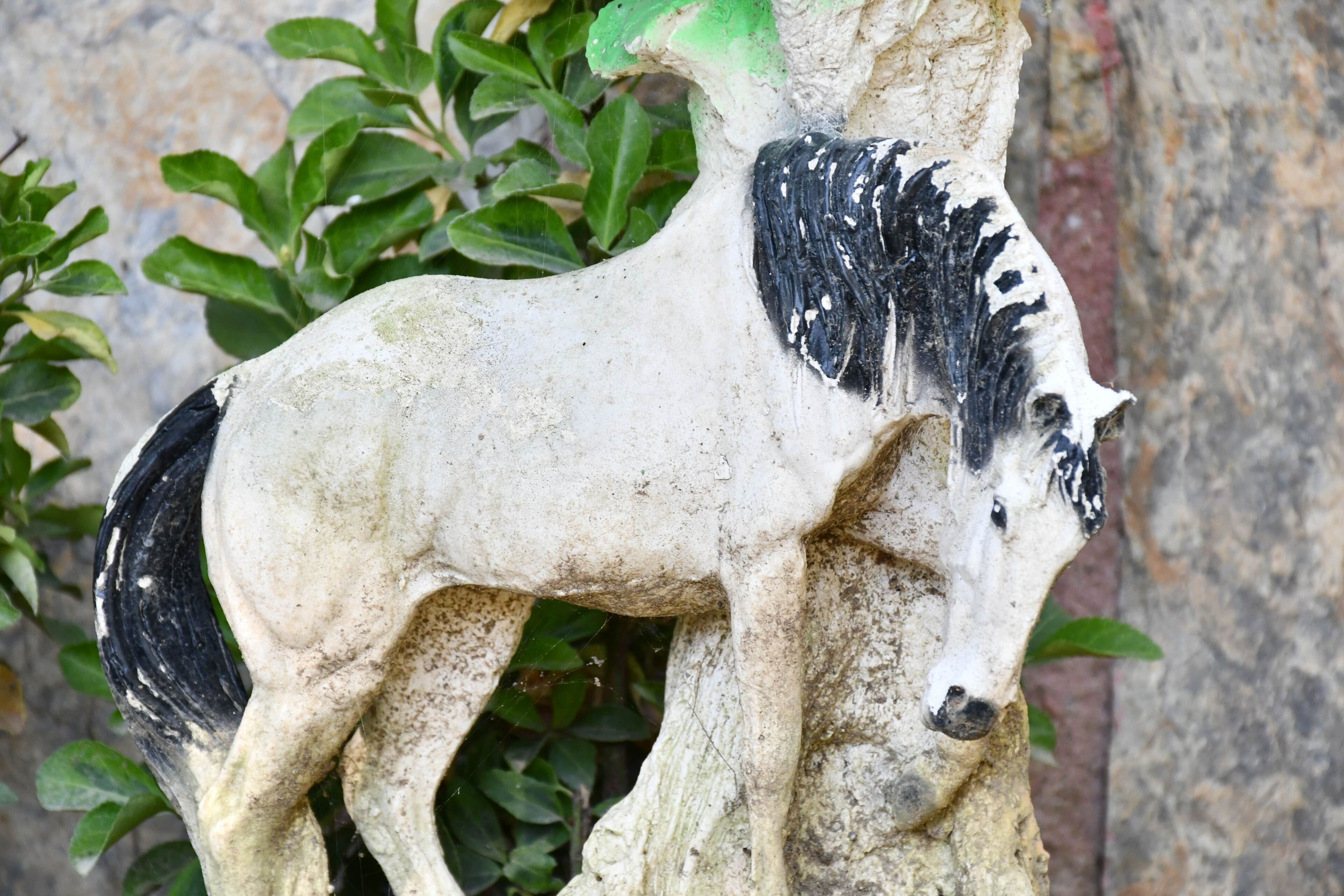 A stone horse statue mounted on a tree trunk.