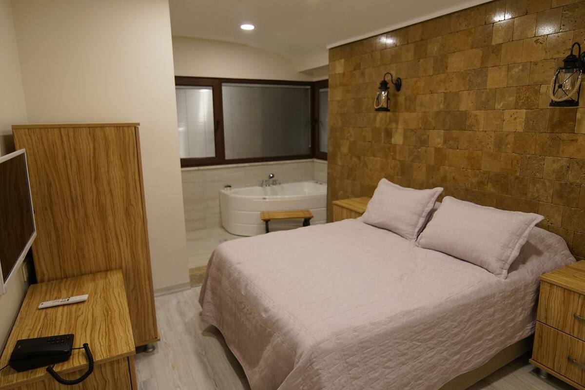 A bedroom with a bed, bedside table, and a TV stand.