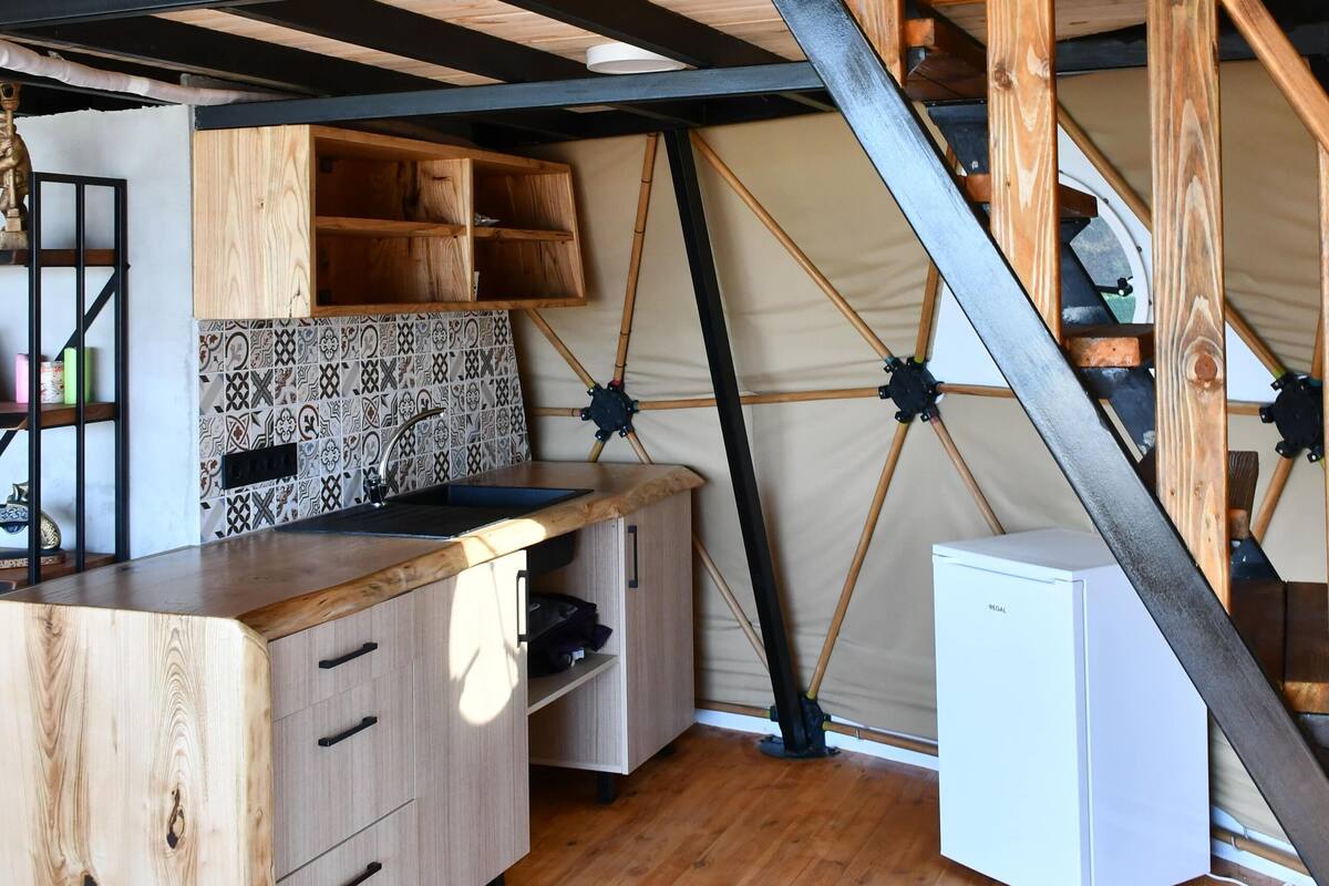 A compact kitchen with wooden cabinetry, a built-in sink, and a small refrigerator.