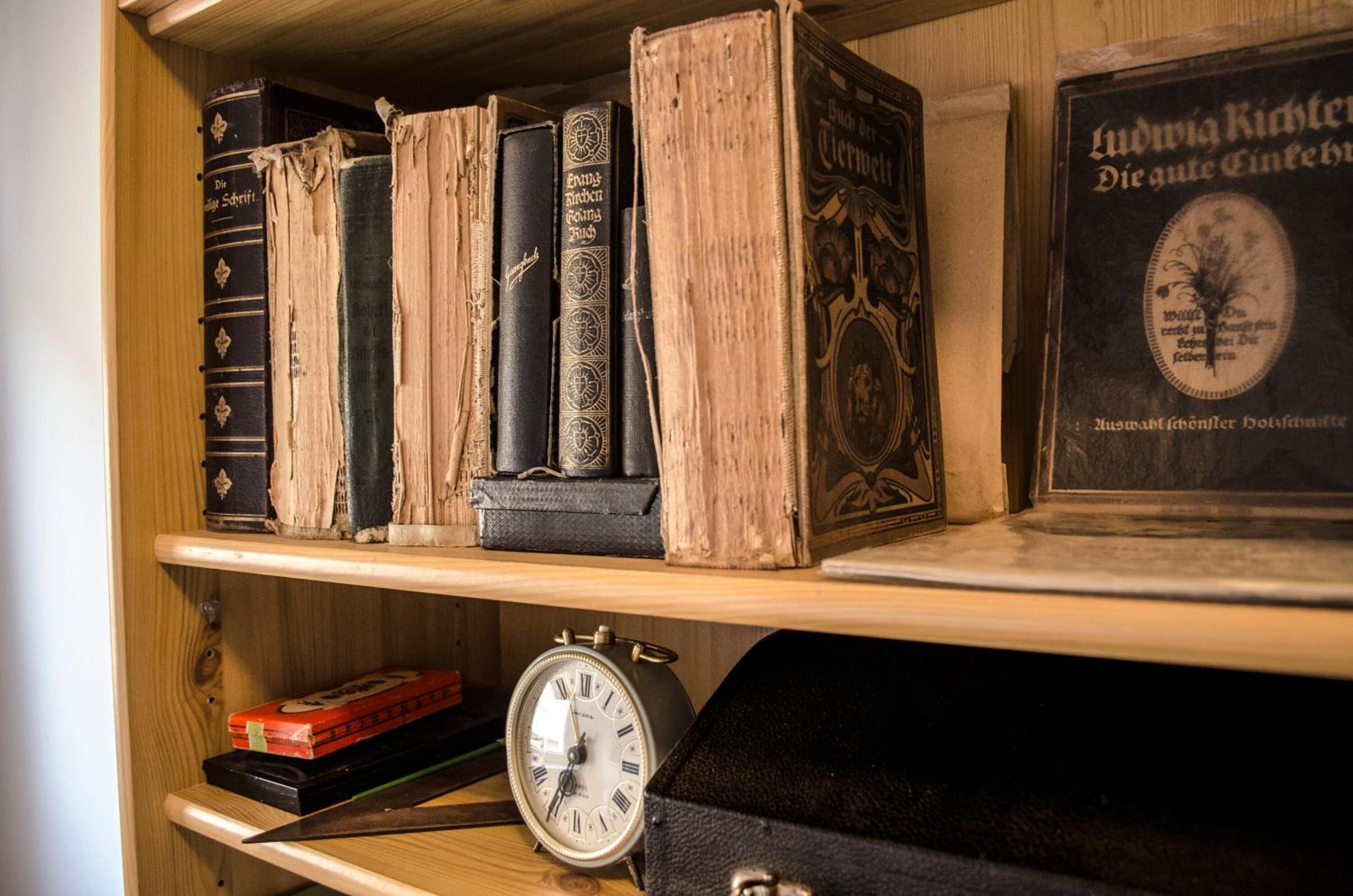 Una estantería de madera con libros antiguos y un cuadro enmarcado.