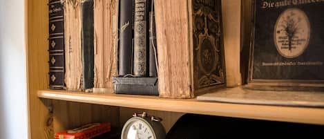 Una estantería de madera con libros antiguos y un cuadro enmarcado.