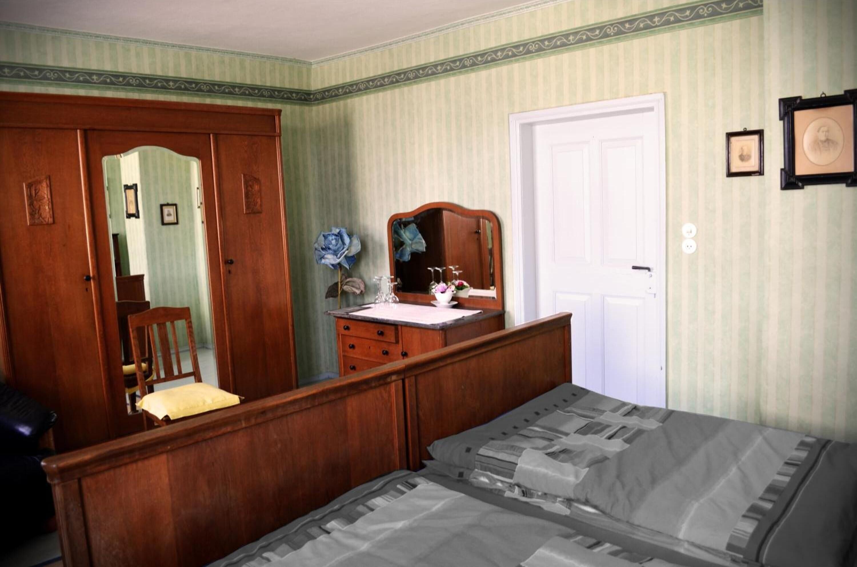 Un dormitorio con cama de madera, cómoda, espejo y puerta.
