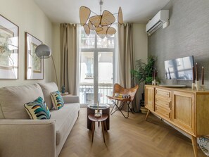 A living room with a sofa, a coffee table, a TV, a cabinet, and a balcony with curtains.