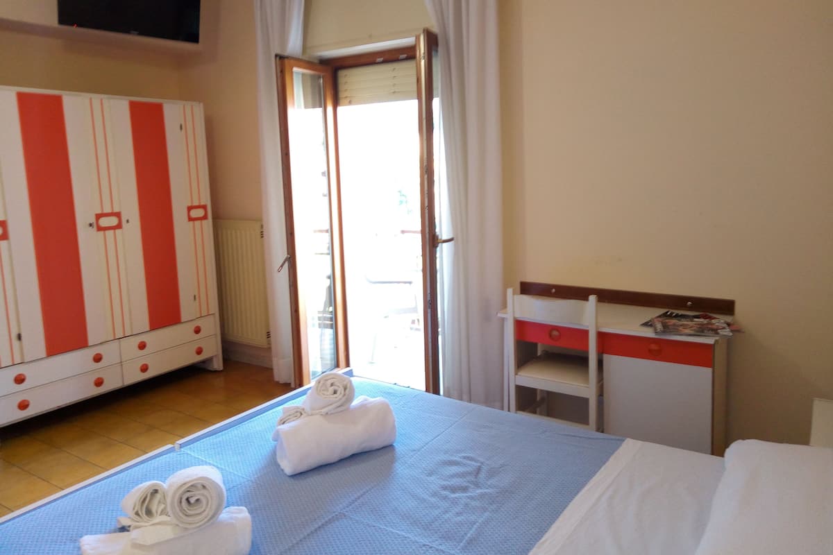A hotel room with a bed, a desk, and a wardrobe.