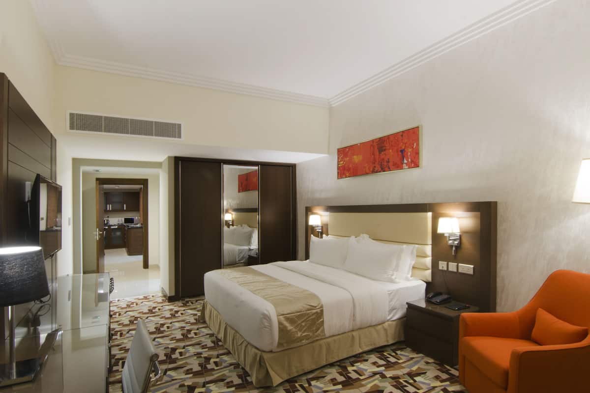 A hotel room with a bed, a TV, a desk, and a chair.